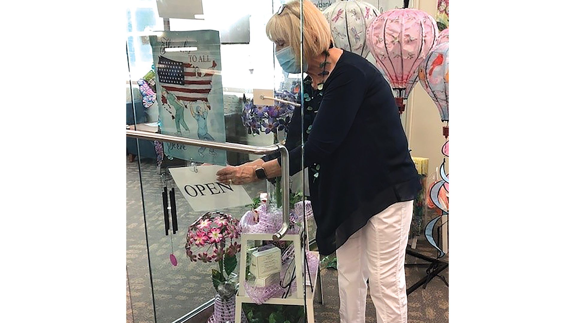 Evelyn Glabicky, gift shop manager, hangs an ‘open’ sign on the facility at Baystate Wing Hospital. The gift shop had been closed due to COVID-19 precautions.